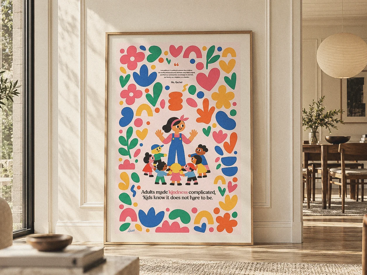 The poster framed in pale wood, leaning against a panelled wall in a sunlit room, bright cut paper shapes around a teacher and a ring of kids.
